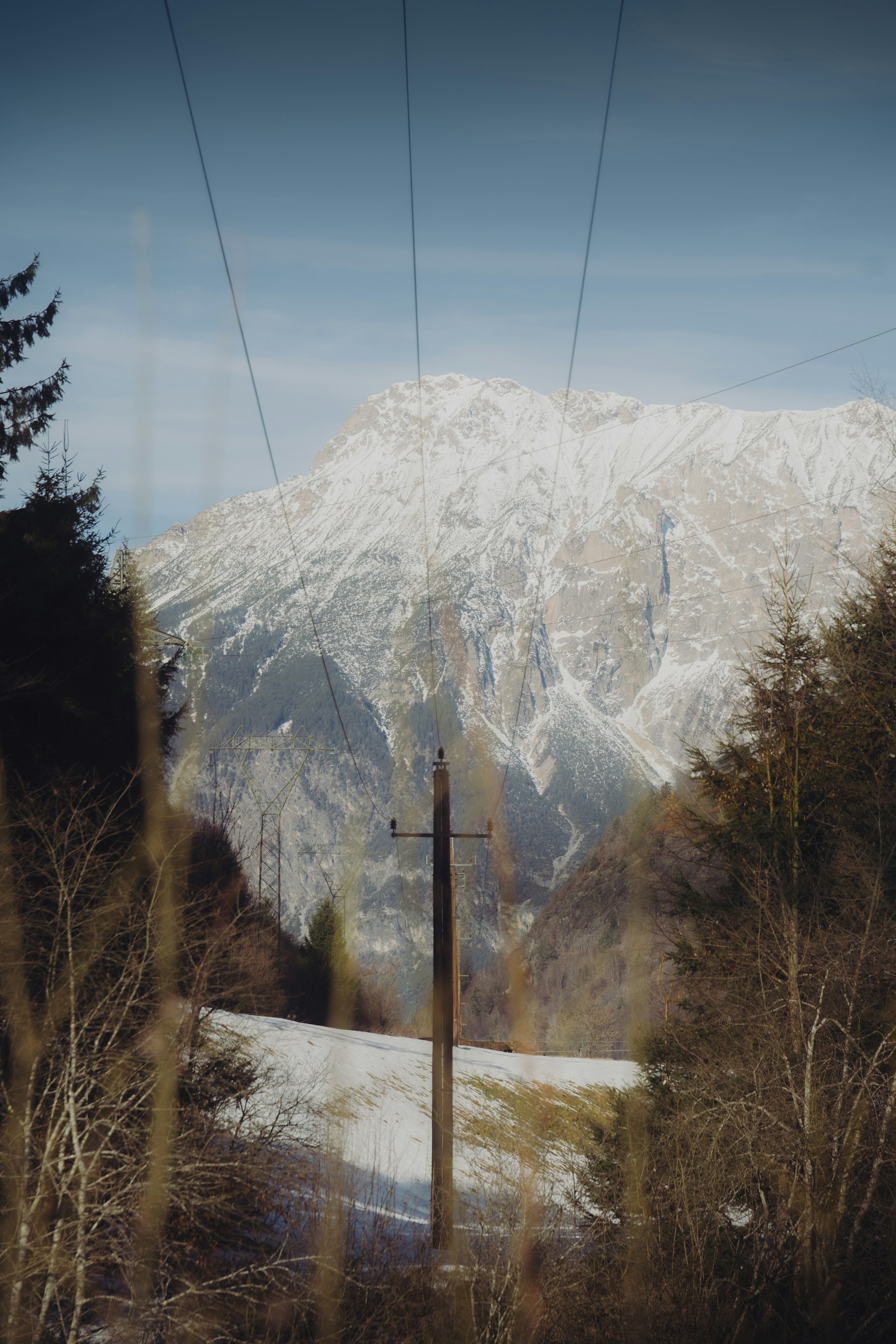 Power line leading towards a snow-covered Alpine peak
